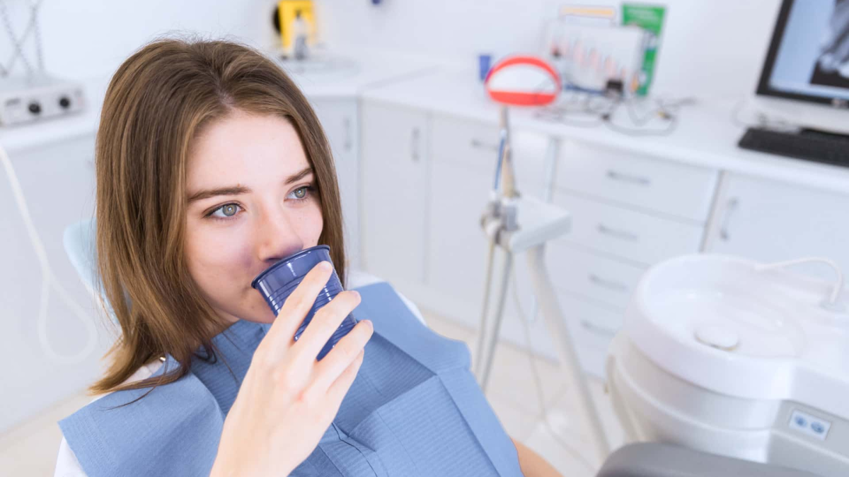 Paciente tomando agua en sillón de Allegra dental. Prevención de enfermedades